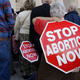 A woman carries an anti-abortion sign on her back during a rally at the Arkansas state Capitol in Little Rock, Ark., Sunday, Jan. 18, 2015
